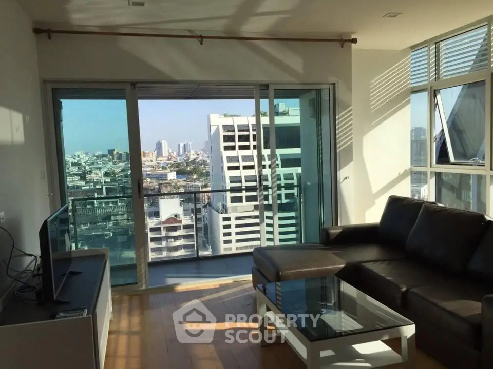Modern living room with city view, featuring sleek furniture and large windows for natural light.
