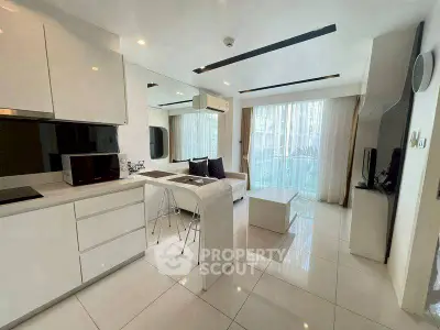 Modern open-plan living room and kitchen with sleek white design and natural light.