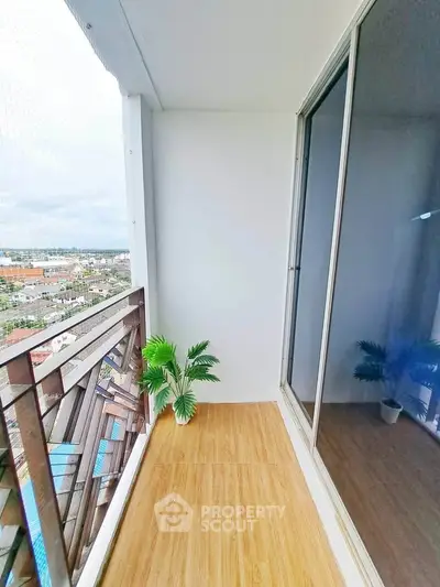 Spacious balcony with wooden flooring and city view, perfect for relaxation.
