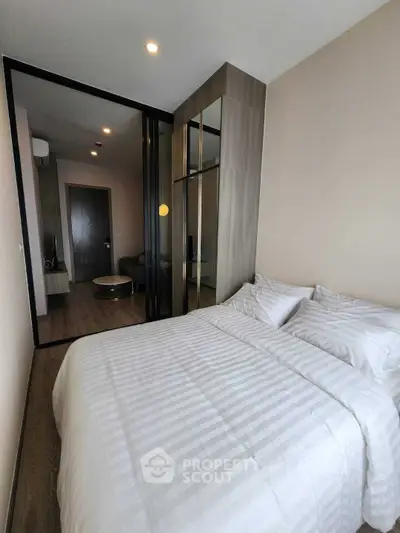Modern bedroom with sleek design and mirrored wardrobe in a stylish apartment.