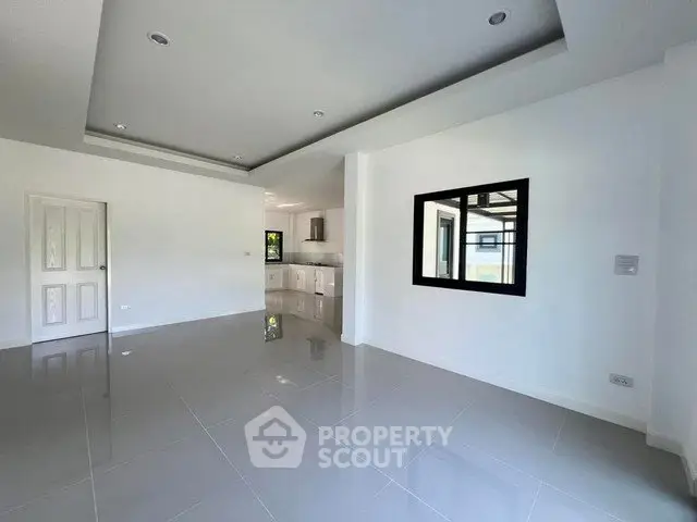Spacious modern living room with sleek tile flooring and open kitchen layout.