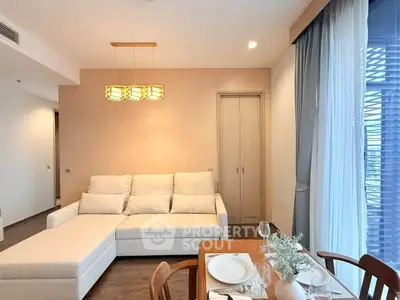 Modern living room with cozy white sofa and elegant dining area, featuring warm lighting and stylish decor.
