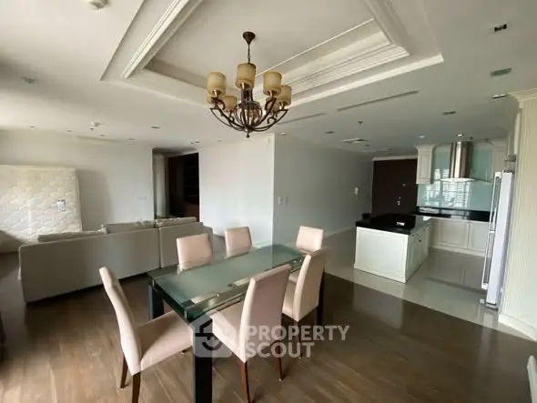 Spacious open-plan living and dining area with elegant chandelier and modern kitchen.
