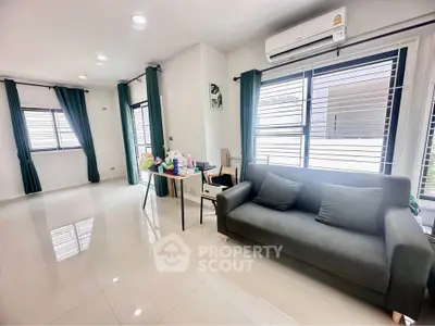 Spacious modern living room with sleek design and abundant natural light, featuring a comfortable sofa and air conditioning.
