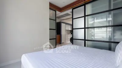 Modern bedroom with sliding glass doors and striped bedding in a stylish apartment.