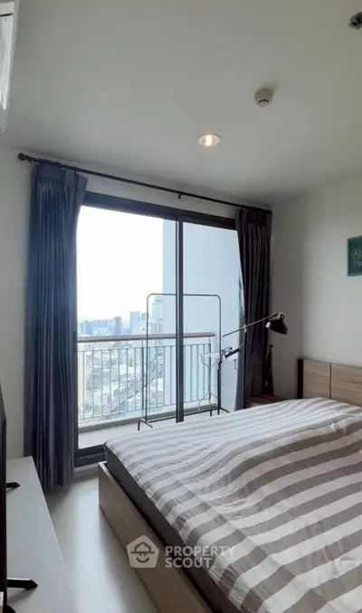 Modern bedroom with city view and large window, featuring stylish decor and cozy ambiance.