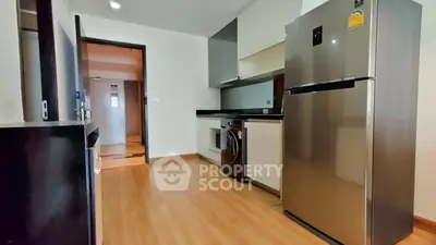 Modern kitchen with sleek appliances and wooden flooring in a stylish apartment.