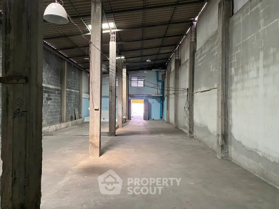 Spacious industrial warehouse with high ceilings and concrete pillars, ideal for storage or manufacturing.