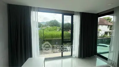 Spacious living room with large windows offering lush green views