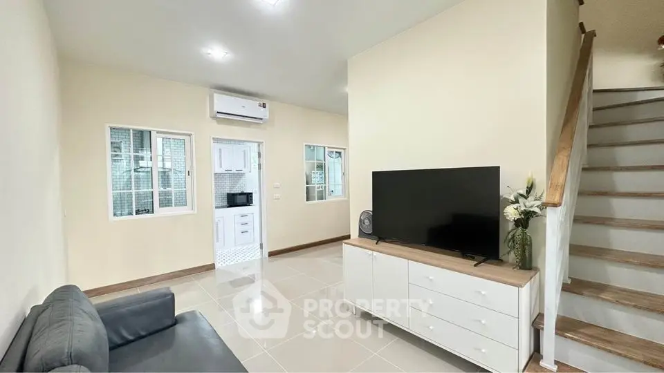 Modern living room with sleek TV setup and adjacent kitchen view