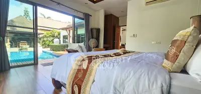 Luxurious bedroom with pool view in tropical villa, featuring elegant decor and abundant natural light.