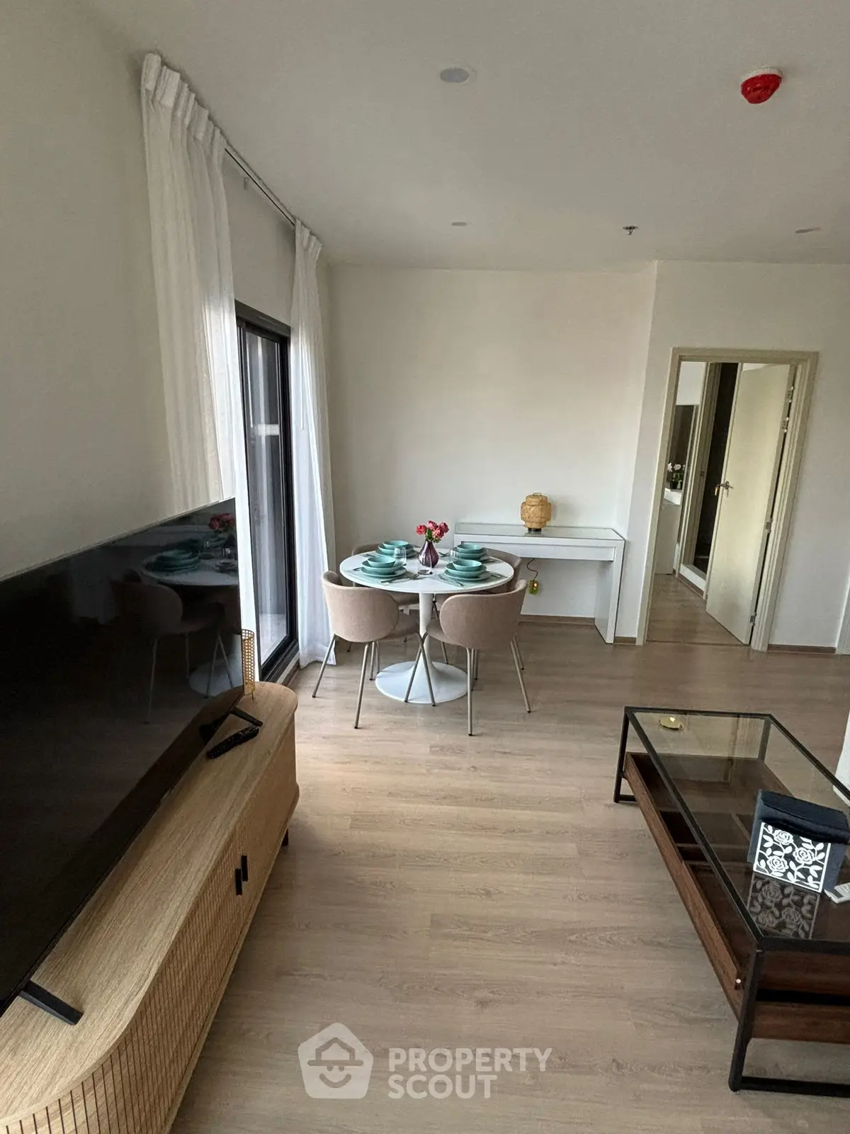Modern living room with stylish furniture and dining area, featuring a large TV and elegant decor.