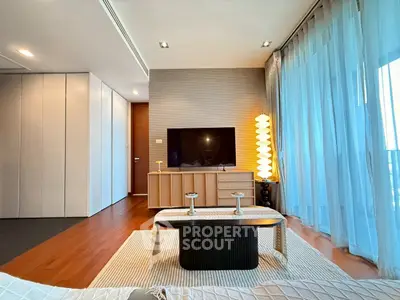 Modern living room with stylish decor and large TV, featuring floor-to-ceiling windows and elegant lighting.