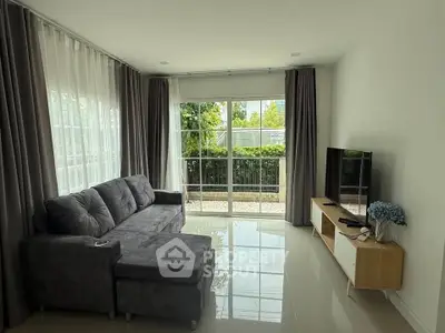 Spacious living room with modern sofa and large windows overlooking garden