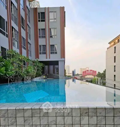 Stunning rooftop infinity pool with city skyline views in modern apartment complex.