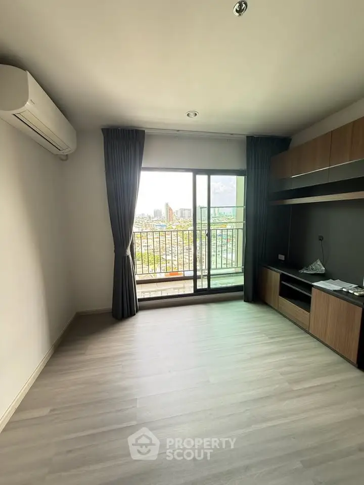 Spacious living room with large window and city view, featuring modern built-in storage and air conditioning.