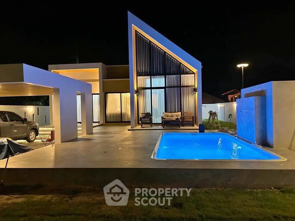 Stunning modern villa with illuminated pool and unique architectural design at night.