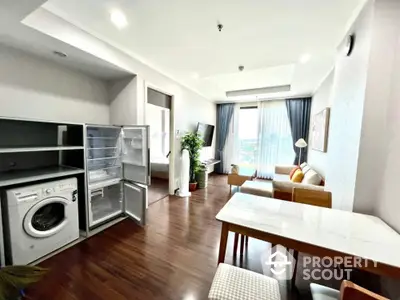 Modern open-plan living room with washing machine and fridge, featuring elegant decor and natural light.