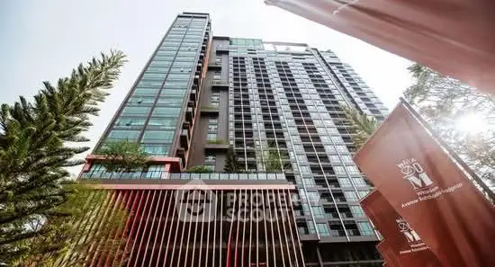 Modern high-rise building with sleek architecture and lush greenery in urban setting.