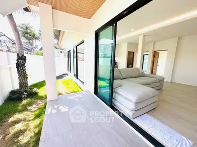 Modern living room with large sliding glass doors opening to a lush garden, featuring a spacious sectional sofa.