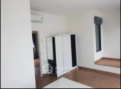 Spacious bedroom with modern wardrobe and large window for natural light.
