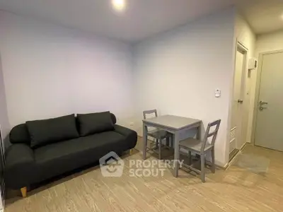 Modern living room with sleek black sofa and compact dining set in a cozy apartment.