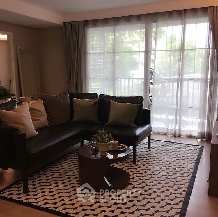 Stylish living room with modern decor and large window overlooking balcony.