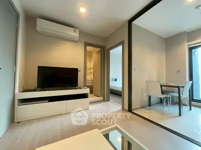 Modern living room with sleek furniture and open layout, featuring a TV and dining area.