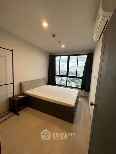 Spacious bedroom with large windows offering stunning city views