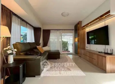 Spacious living room with modern decor and large TV, featuring a cozy sofa and elegant lighting.