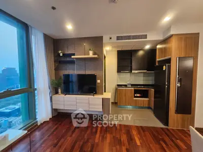 Modern living room with open kitchen and city view, featuring sleek wooden flooring and contemporary furnishings.
