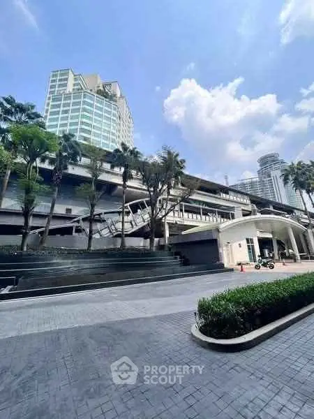 Modern urban building exterior with lush landscaping and clear blue sky