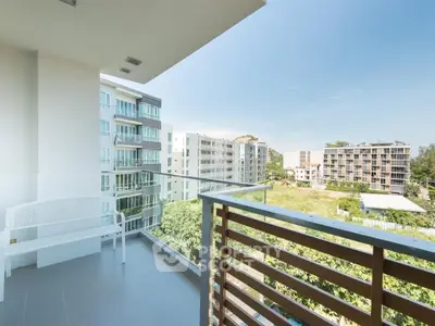 Spacious balcony with modern railing offering scenic views of nearby residential buildings.