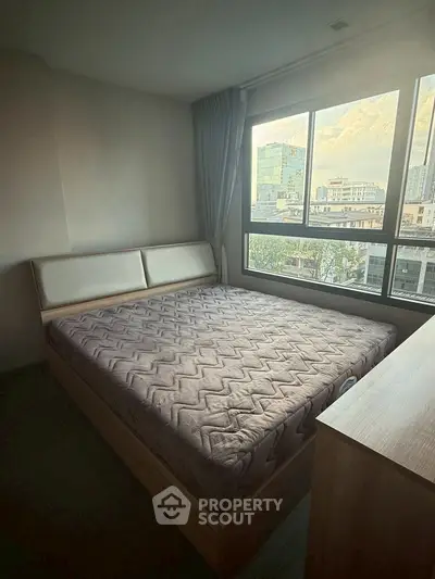 Cozy bedroom with large window offering city view, featuring a comfortable bed and modern decor.