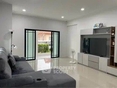 Spacious modern living room with sleek furniture and large sliding doors opening to a garden view.