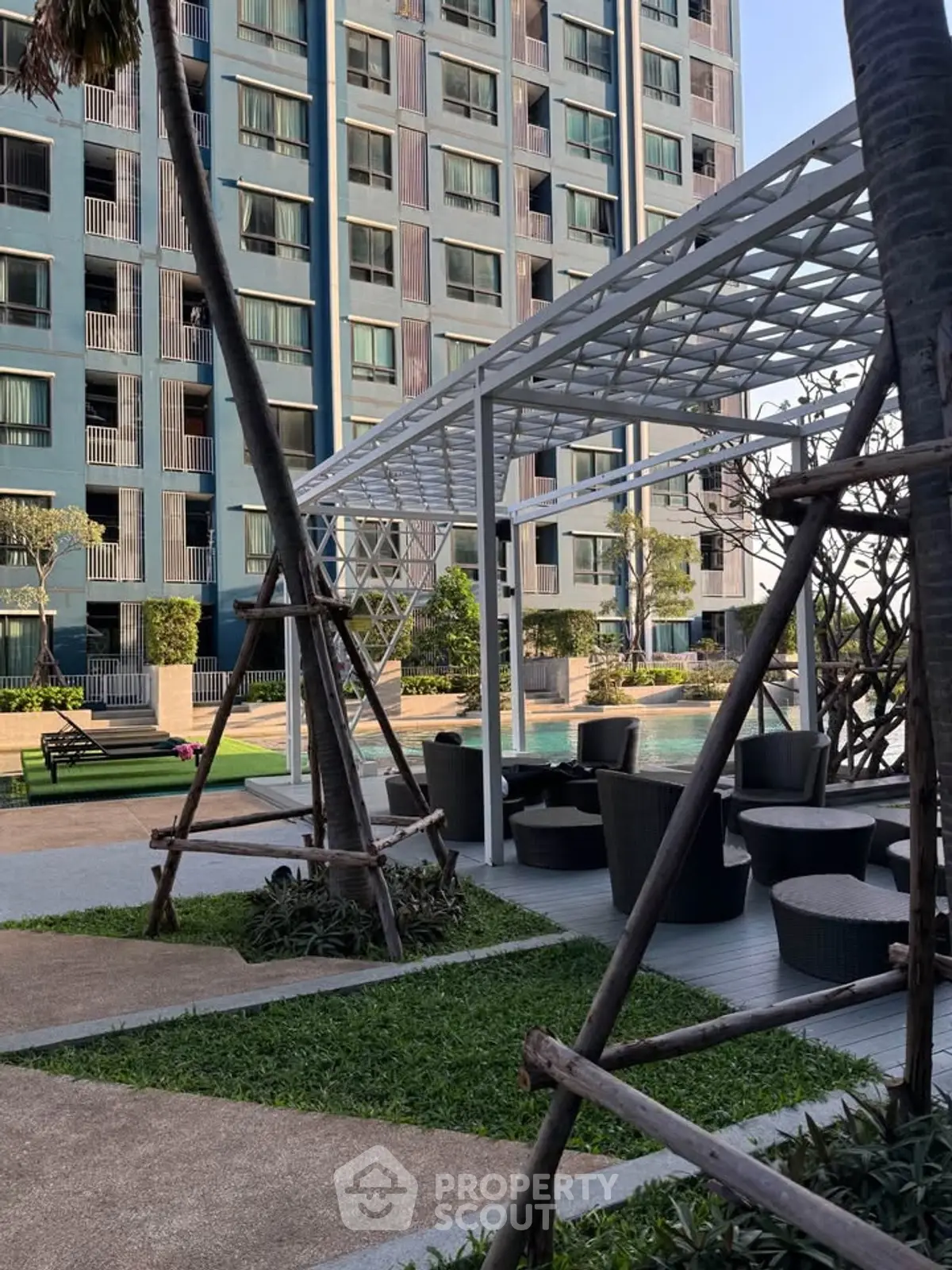 Modern apartment building with stylish outdoor seating area and poolside view.