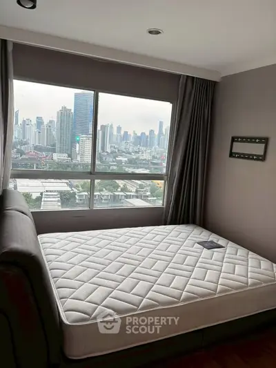 Spacious bedroom with city skyline view and large window, perfect for urban living.