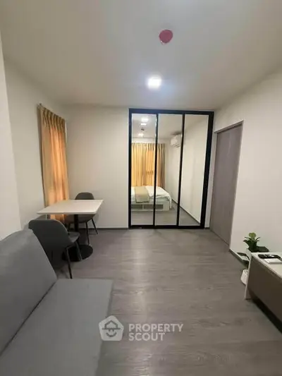 Modern studio apartment with mirrored wardrobe and cozy seating area.