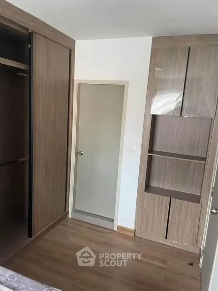 Modern bedroom with wooden flooring and built-in wardrobe, showcasing sleek design and ample storage space.