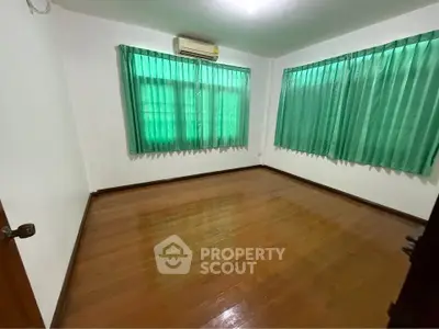 Spacious empty bedroom with wooden floors and green curtains, ready for customization.