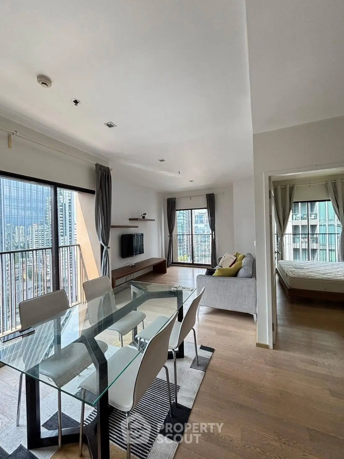 Modern open-plan living room with dining area and city view, featuring sleek furniture and large windows.