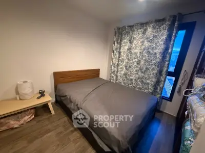 Cozy bedroom with wooden flooring and large window, featuring a comfortable bed and elegant curtains.