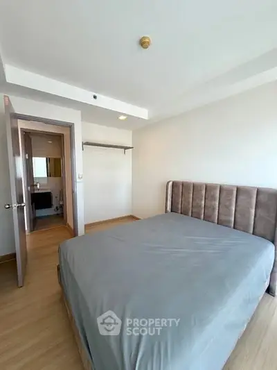 Spacious bedroom with modern design and ample natural light, featuring a comfortable bed and wooden flooring.