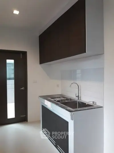 Modern kitchen with sleek cabinetry and stainless steel sink in a contemporary apartment.