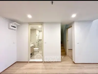 Modern minimalist interior with bathroom and staircase, showcasing sleek design and bright lighting.