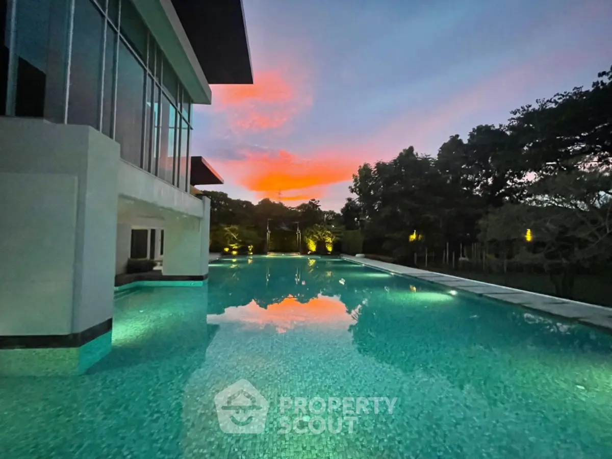 Stunning poolside view at sunset with modern architecture and lush greenery.