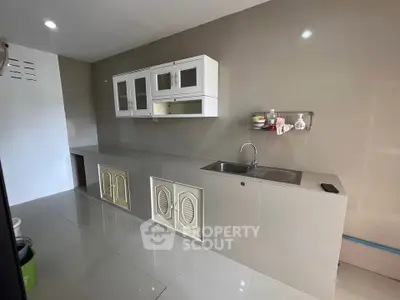 Modern kitchen with sleek cabinetry and stainless steel sink in minimalist design.