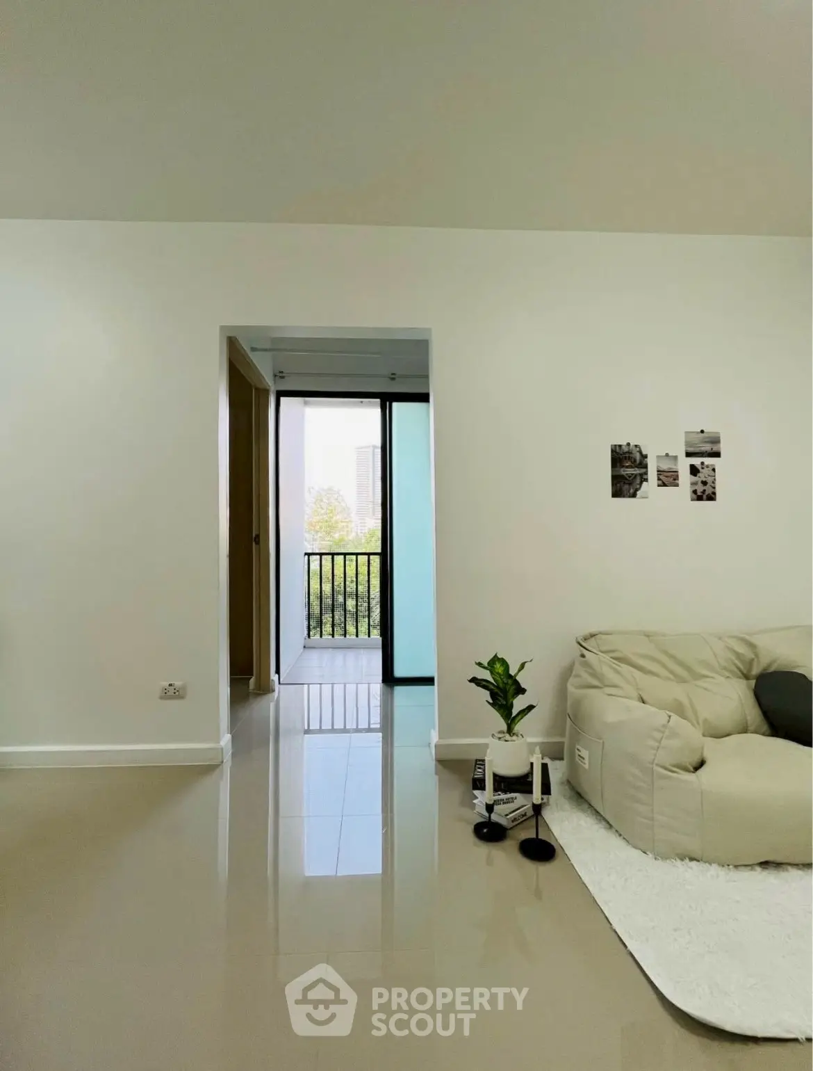 Modern living room with sleek flooring and cozy seating, leading to a balcony with city view.