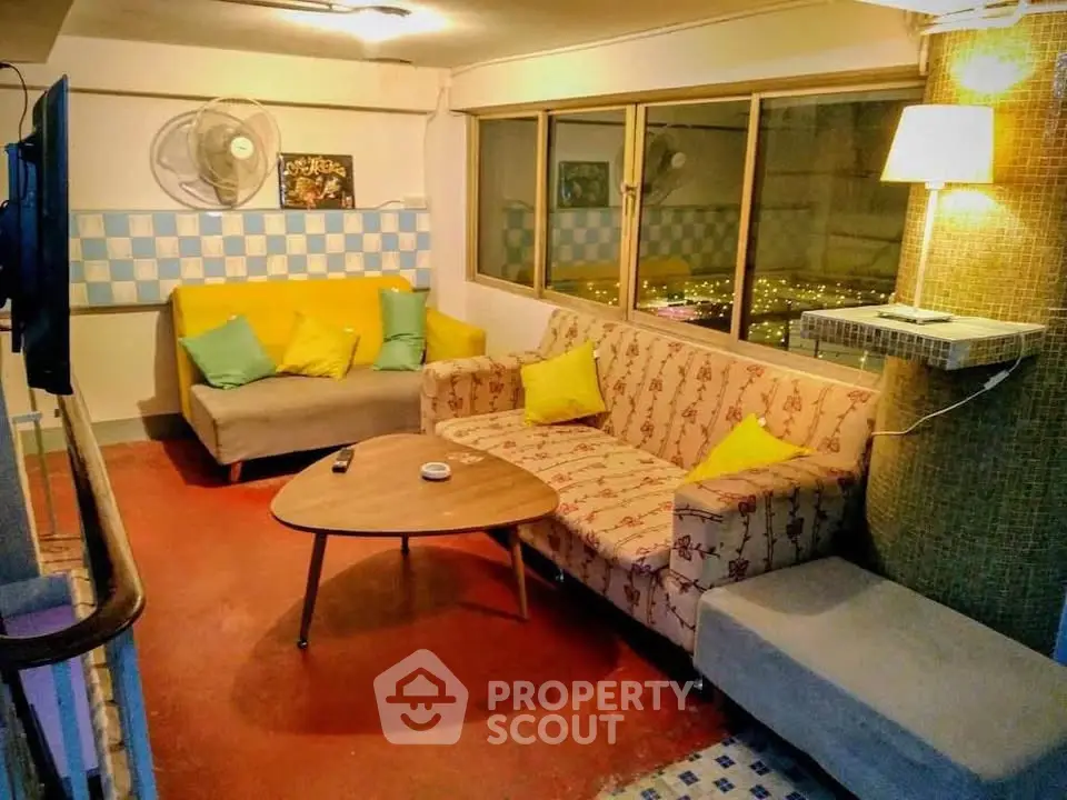 Cozy living room with vibrant decor and city view, featuring a patterned sofa and modern lighting.