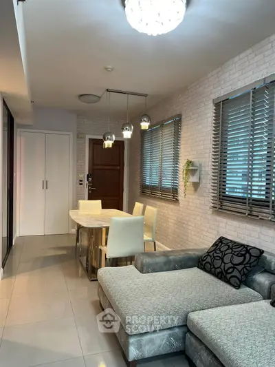 Modern living room with stylish decor and dining area, featuring a cozy sofa and elegant lighting.